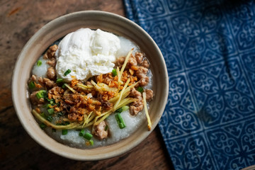 Thai style breakfast pork rice soup with egg on wood table. Copy space put your text on background.