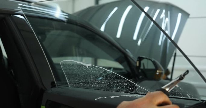 Close up of paint protection film installation on modern luxury car. PPF is polyurethane film that wrap car paint to protect paint surface from stone chips, bug splatter, and abrasion.