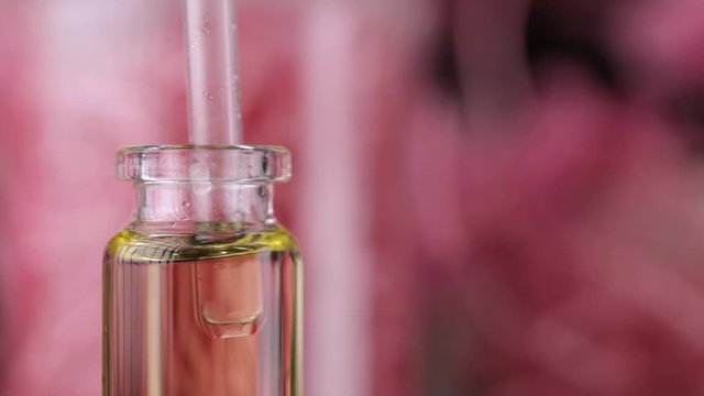 Blend of essential oils closeup. Making some aroma liquids, perfume. Drops falling from pippet to little glass bottle. Slowmotion. Liquid ingredients, body care production, cosmetology.