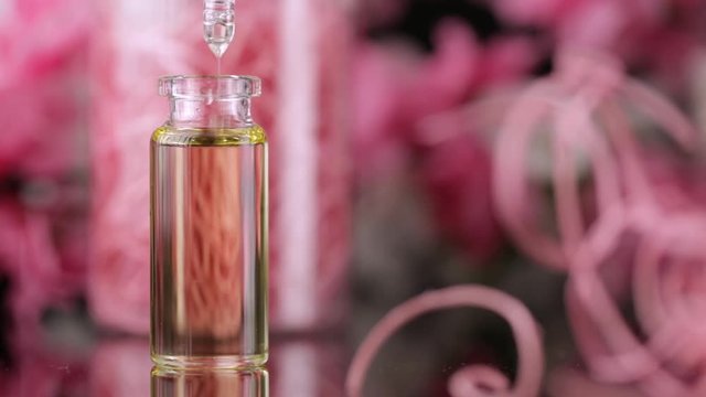 Blend of essential oils closeup. Making some aroma liquids, perfume. Drops falling from pippet to little glass bottle. Slowmotion. Liquid ingredients, body care production, cosmetology.