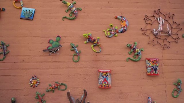 Colorful Ceramic Mexican Artworks Hanging On The Brick Wall In Tubac, Arizona - Panning Shot