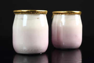 Yogurt with jam in small glass jar with aluminium foil seal cap