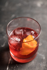 Red traditional old fashioned cocktail with orange zest on the rustic background. Selective focus. Shallow depth of field.