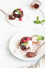 Delicious chocolate fondant or lava cake with cream, raspberries and cream, light grey concrete background. Hot chocolate dessert (pudding) with liquid center. Fondant au chocolate. 