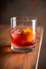 Red traditional old fashioned cocktail with orange zest on the rustic background. Selective focus. Shallow depth of field.