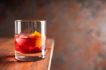 Red traditional old fashioned cocktail with orange zest on the rustic background. Selective focus. Shallow depth of field.