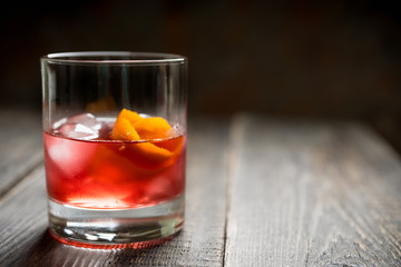 Red traditional old fashioned cocktail with orange zest on the rustic background. Selective focus. Shallow depth of field.
