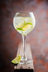 Rum based cocktail with lime in wine glass (variation of cuba libre) on the rustic background. Selective focus. Shallow depth of field.