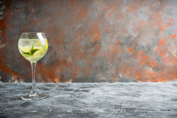 Rum based cocktail with lime in wine glass (variation of cuba libre) on the rustic background....