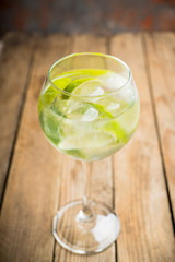 Rum based cocktail with lime in wine glass (variation of cuba libre) on the rustic background. Selective focus. Shallow depth of field.