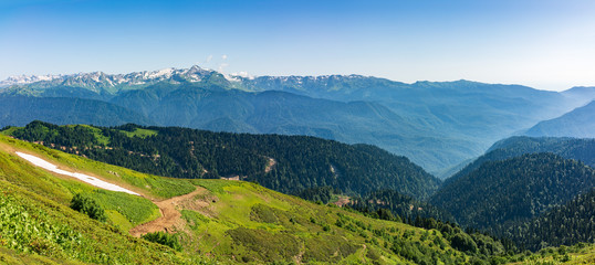Panoramic view over the Green Valley, surrounded by high mountains with snow on a clear summer day.