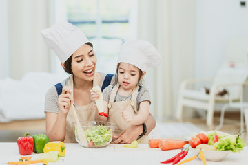 Happy family mom teaching cute girl preparing and cooking healthy salad for the first time. first lesson and healthy lifestyle concept.