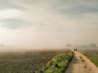 Country view in the middle of fog with a couple walking o a road