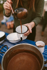 Fototapeta na wymiar woman pouring hot chocolate into a camping mug outdoors
