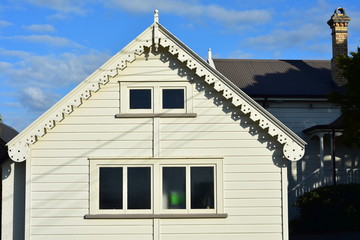 White vintage wooden studio in front of wooden house with corrugated iron roof and brick chimney.