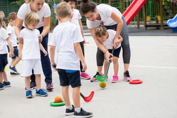Group of children playing hockey within polygon.  Sport school. Coach helping