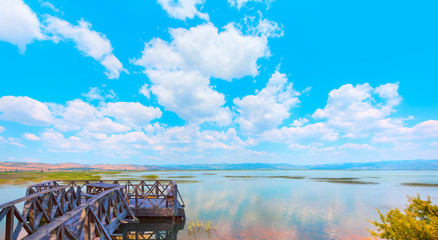 Old wooden pier in the Marmara lake on the background cloudy blue sky