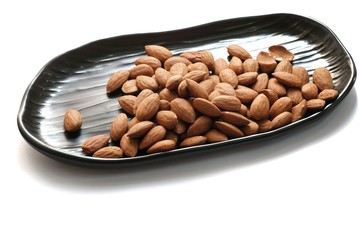 The almonds on black tray on isolated white background.