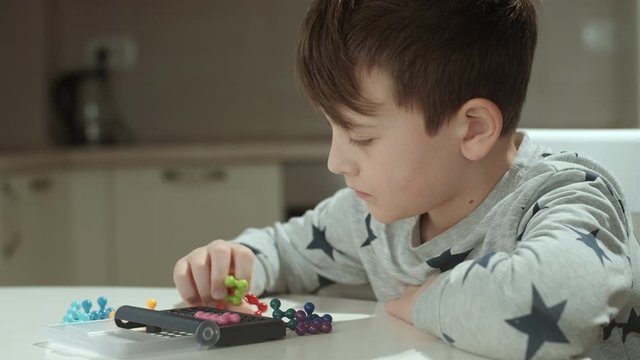 Concentrated boy in grey sweatshirt playing logic game at home

