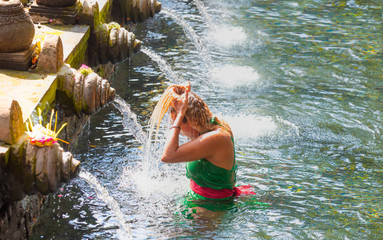 Young girls is praying in holy spring water of sacred pool - Pura Tirtha Empul Temple, Indonesia