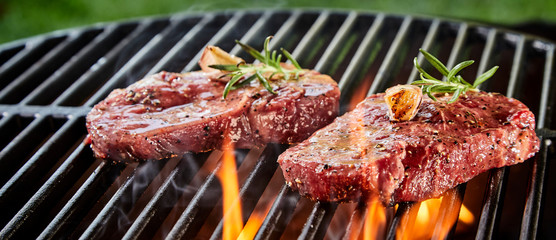 Succulent slices of raw beef steak on a BBQ