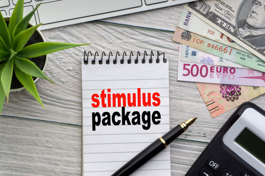 STIMULUS PACKAGE Text With Notepad, Keyboard, Decorative Vase, Fountain Pen, Calculator And Banknotes Currency On Wooden Background. Business And Copy Space Concept