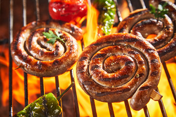 Coils of succulent spicy sausage grilling on fire