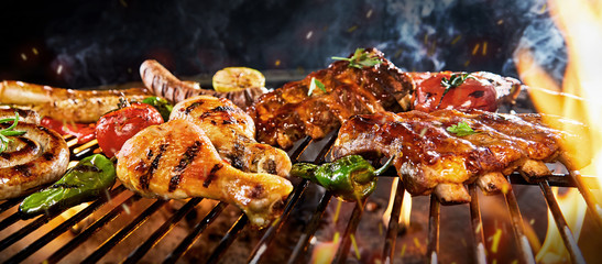 Chicken drumsticks, pork ribs and sausage on a BBQ