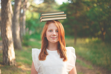 red-haired girl in a white dress with books on her head
