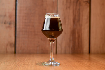 Glass of dark beer on light wooden background. Alcohol drink. Food photography concept, copy space.