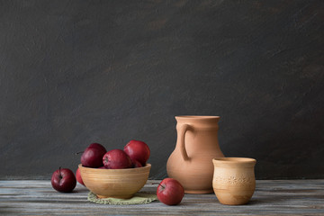 Natural light from a window. Set of ceramic dishes and red apples on a wooden table. Still life in a rustic style. 