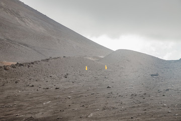 Top of crater Mount Etna volcano, frozen cold lava smokes, thick clouds