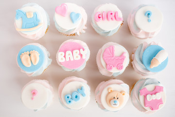 Fototapeta na wymiar Is it a boy or a girl concept. Twins baby shower decorations. Baby shower cupcake for a boy and a girl. Blue and pink cupcake with mastic.