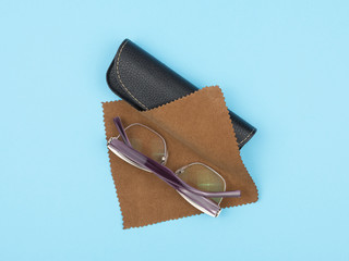 Glasses, case and a cloth to care for the lenses on a blue background.