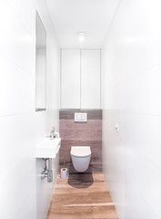 Naklejka na ściany i meble Small bathroom interior with white tiles and fake wooden floor. Original designed toilet space with modern minimal pieces.