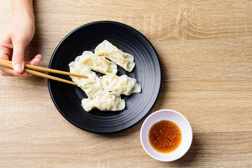 Steamed wonton dumpling stuffed with minced pork and shrimp eating with sesame oil sauce by using chopsticks, Asian food, Top view