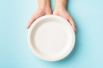 Biodegradable plate, Compostable plate or Eco friendly disposable plate holding by hand on pastel color background