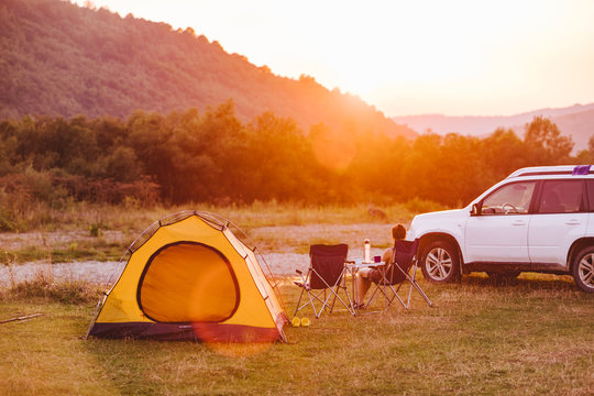 woman looking at sunset above mountains river. camping concept