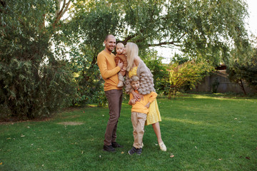 Fototapeta premium family in nature, summer or autumn, green grass trees in green leaves, a pond in nature, mom blonde in a yellow dress, dad, husband, older son and youngest son, two children, a large and happy family