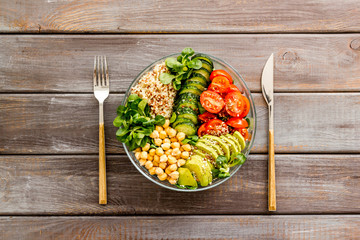 Veggie bowl. Vegetable salad with quinoa, avocado, tomato, spinach and chickpeas - on wooden table. Top view