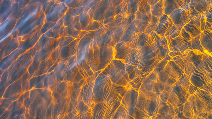 Glare of the sun and waves at the bottom of the river