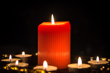 Close up of one big and six small burning candles with dark background