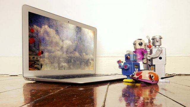 a group of toy robots watching a film on a laptop Don't panic 