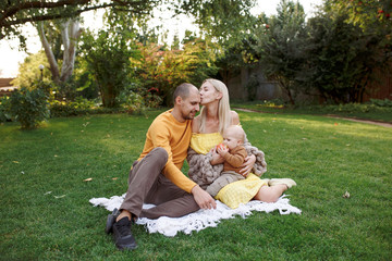 
family in nature, summer or autumn, green grass trees in green leaves, a pond in nature, mom blonde in a yellow dress, dad, husband, older son and youngest son, two children, a large and happy family