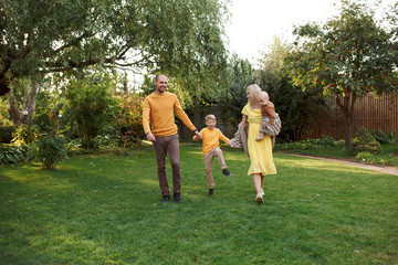 Obraz premium family in nature, summer or autumn, green grass trees in green leaves, a pond in nature, mom blonde in a yellow dress, dad, husband, older son and youngest son, two children, a large and happy family