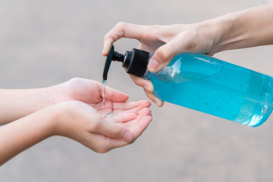 Coronavirus or COVID-19 pandemic prevention, Mother put hand sanitizer to hand daughter wash hands with Alcohol based hand sanitizer and , rubbing nails and fingers washing frequently .