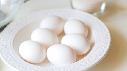 
white chicken eggs in a plate on a white background