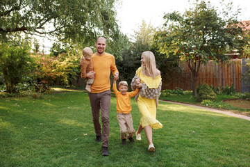 Obraz premium family in nature, summer or autumn, green grass trees in green leaves, a pond in nature, mom blonde in a yellow dress, dad, husband, older son and youngest son, two children, a large and happy family