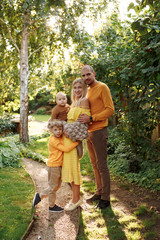 Fototapeta premium family in nature, summer or autumn, green grass trees in green leaves, a pond in nature, mom blonde in a yellow dress, dad, husband, older son and youngest son, two children, a large and happy family