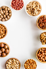 Nuts set in bowls on white background top-down frame copy space